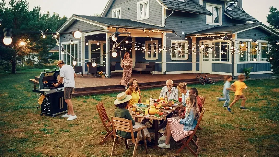 Family gathered around summer BBQ with wooden furniture